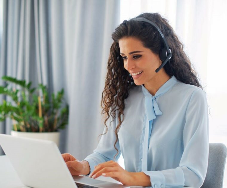 woman talking on headphones and working on a laptop